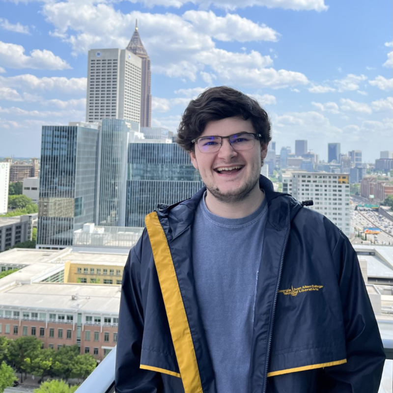 Sean posing in a GT jacket on a rooftop in front of the Atlanta skyline