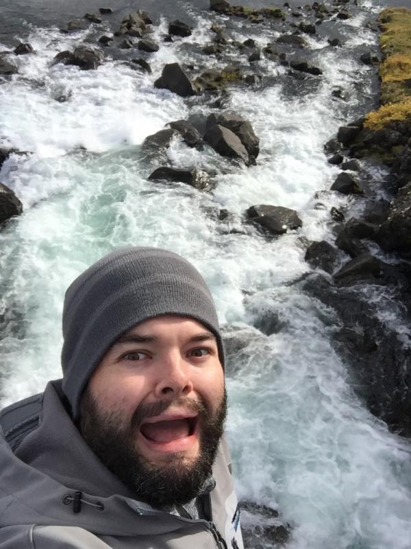 Matthew Miller taking a selfie in front of a rushing river