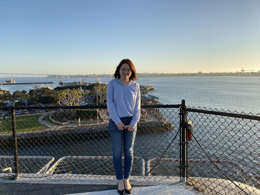 Karen Yan stands outside on a cliff above an ocean