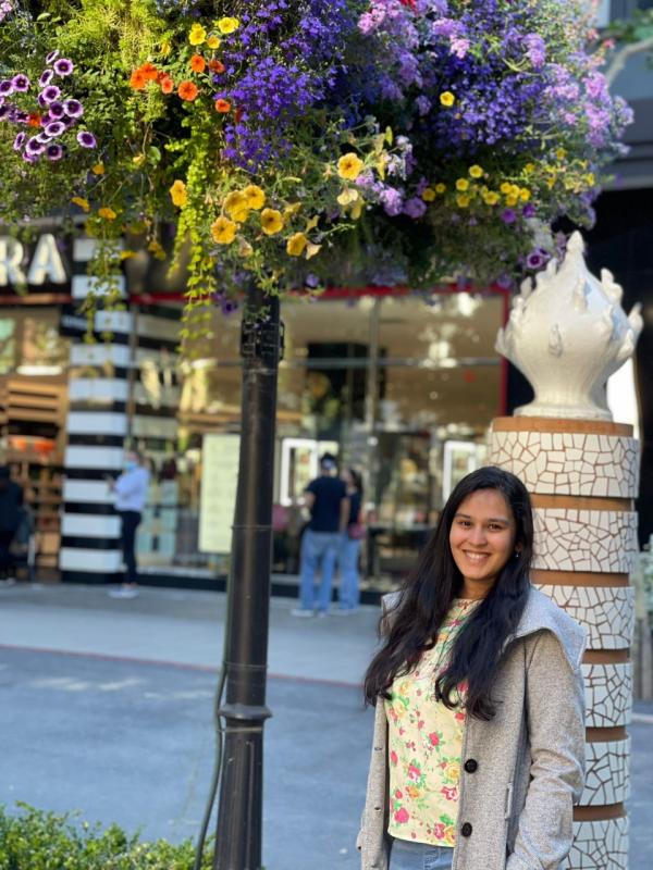 Nupur smiling on a street with flowers overhead